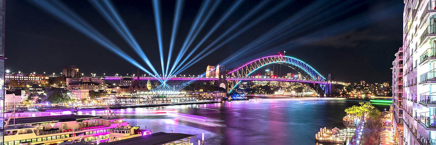 Circular Quay and Sydney Harbour Bridge illuminated with colourful light, during the Vivid Sydney. Photo by RugliG / Shutterstock