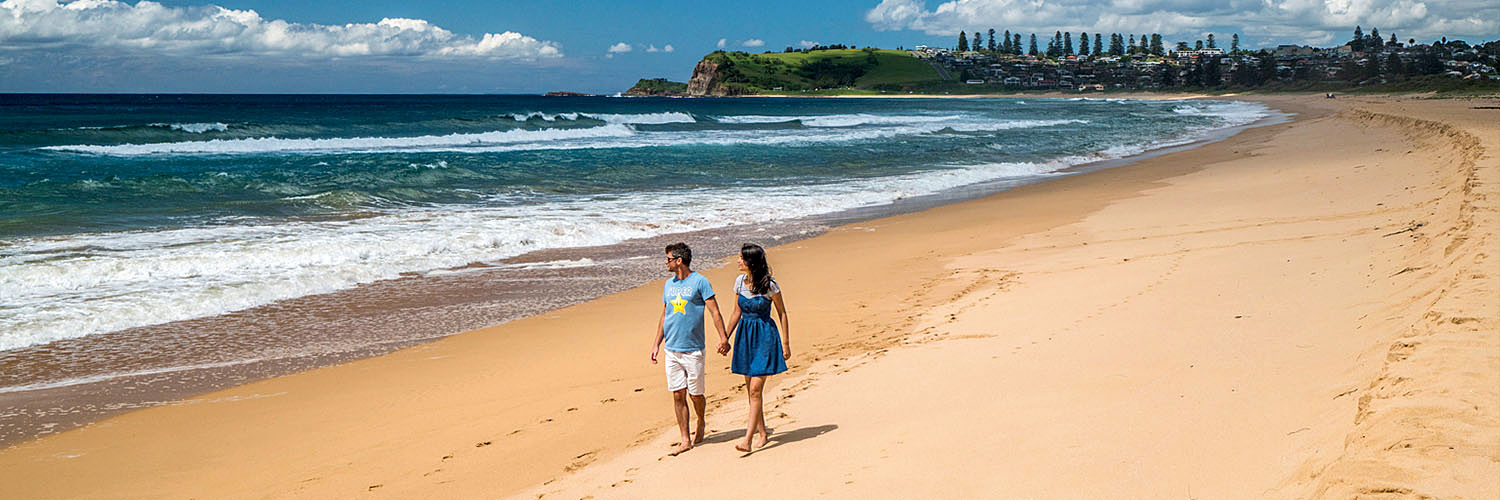 Couple walking along a beach in the Illawarra-Shoalhaven region.