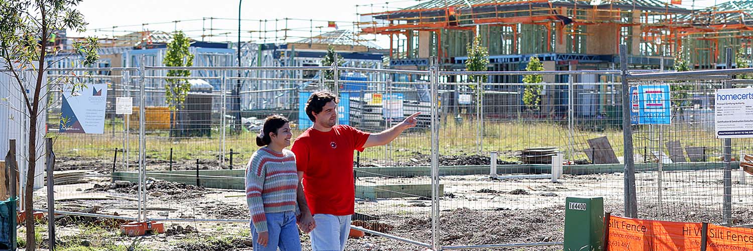 Young couple walking by a new housing development.