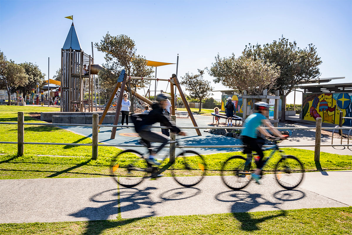 Cyclists ride past Towradgi Beach Park playground. Credit: NSW Department of Planning and Environment