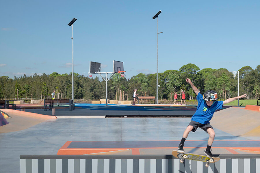 Person skating with basketball courts in background at new park in Beaumont Hills. Credit: NSW Department of Planning, Housing and Infrastructure 