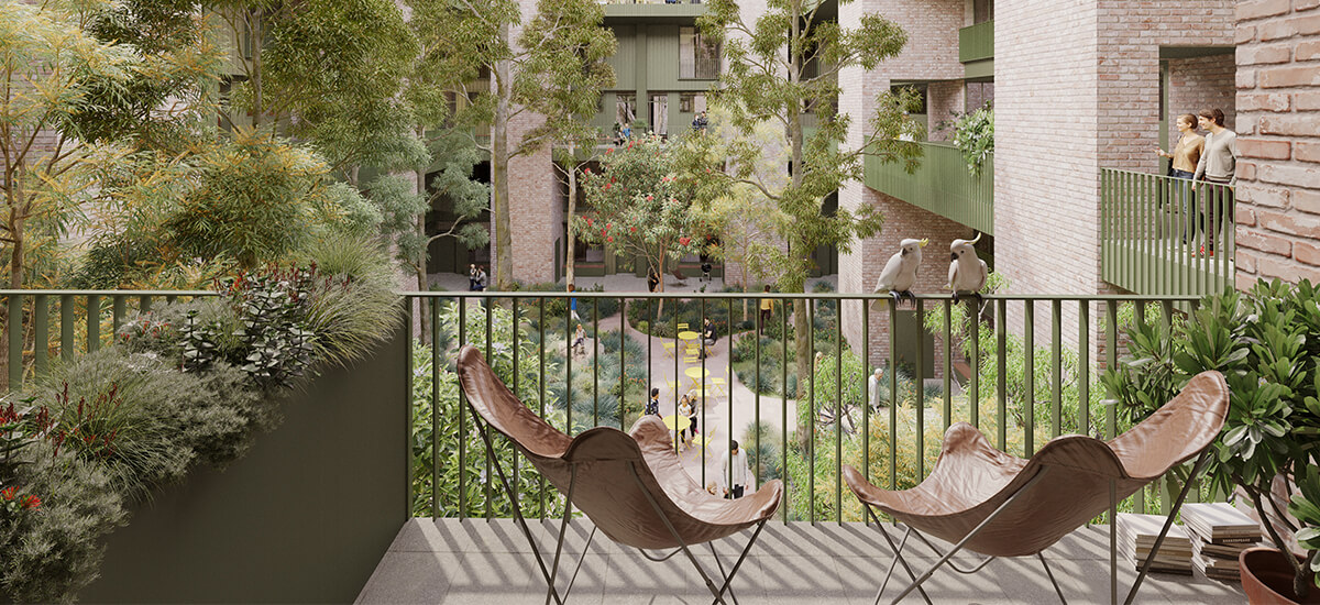 View from an apartment balcony into the central communal courtyard with planting and people walking below and two chairs in the foreground. 
