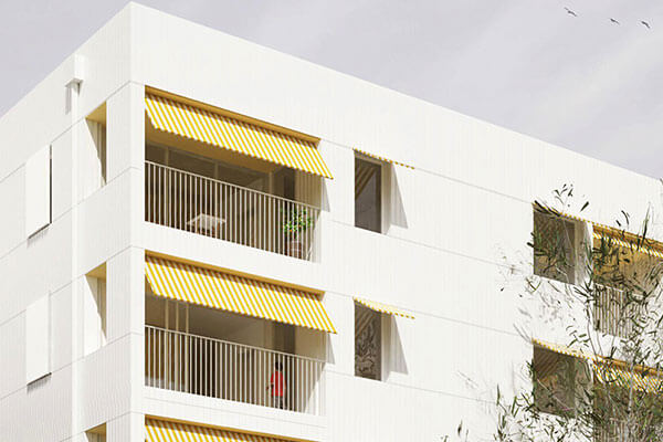Close up of apartment building and striped yellow awnings over balcony. 